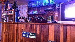 Zona de bar amb barra de fusta i cartell que indica un servei 'CAJA' per VISA i Mastercard.