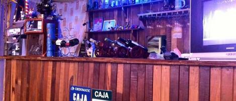 A wooden bar area with a sign indicating a 'CAJA' service for VISA and Mastercard.