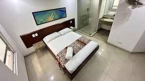 A hotel room with a bed, a shower, a bathroom, and a painting on the wall. - Hotel via 45 Centro (Medellín)
