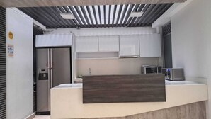 A modern kitchen with white cabinets, a built-in microwave, and a wooden countertop. - Hotel via 45 Centro (Medellín)
