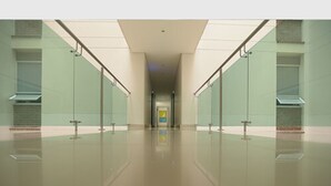 A long, narrow hallway with glass walls and metal railings, leading to a door at the end. - Hotel via 45 Centro (Medellín)