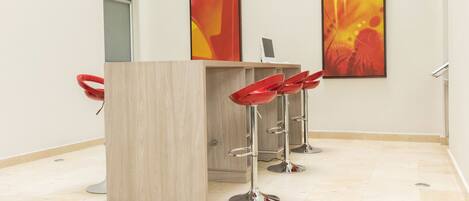 Un área de bar moderna con mostrador de madera y taburetes rojos.