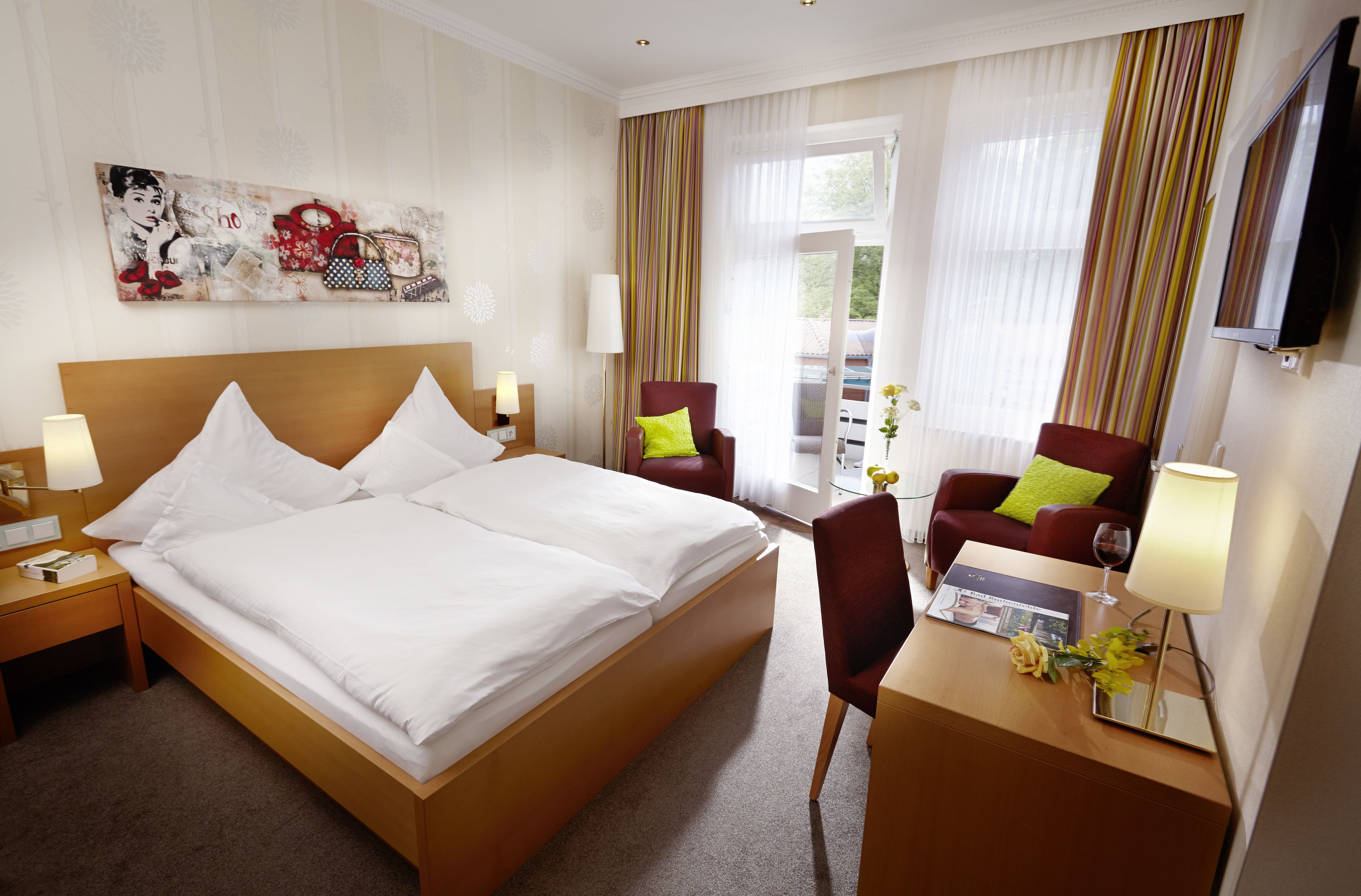 Une chambre d’hôtel avec un grand lit, un bureau avec une lampe, une chaise et un téléviseur fixé au mur.