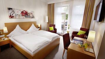 Une chambre d’hôtel avec un grand lit, un bureau avec une lampe, une chaise et un téléviseur fixé au mur.
