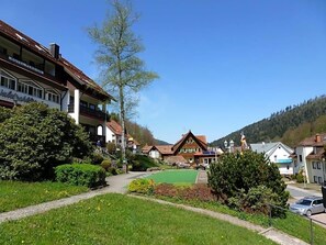 A rural village with traditional houses, a clear sky, and a green field.
