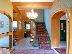 Un vestíbulo de hotel con una gran escalera, un candelabro y una pequeña estatua.