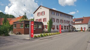 A two-story hotel with a red and white facade, a small attached structure, and a clear sky. - Gasthof & Pension zum Kreuz (Lautenbach)