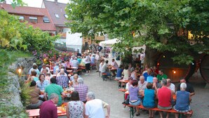 An outdoor dining area with multiple tables and benches, surrounded by greenery and buildings. - Gasthof & Pension zum Kreuz (Lautenbach)