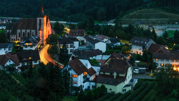 A town with a prominent church, residential buildings, and a road with light trails. - Gasthof & Pension zum Kreuz (Lautenbach)