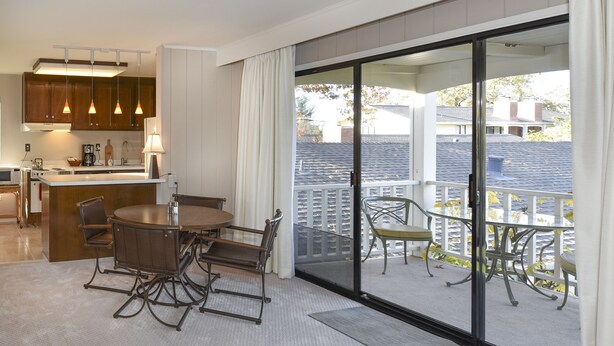 A modern kitchen with a dining area, a sliding glass door to a balcony, and a view of the neighborhood. - 305 Northgate at Silverado in Napa - One Bedroom Condo (Napa)