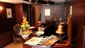 A reception desk with a floral arrangement, a bell, and magazines.