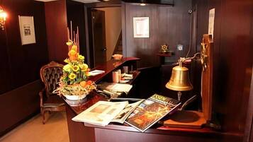 A reception desk with a floral arrangement, a bell, and magazines.