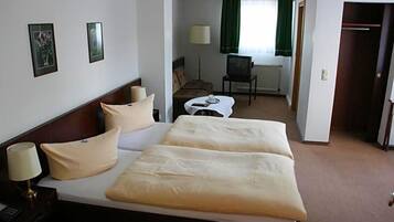 A hotel room with a double bed, bedside tables, a desk with a chair, a television, and a window with curtains.