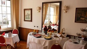 A dining area with tables set for breakfast, featuring a variety of food items and a mirror reflecting the room.