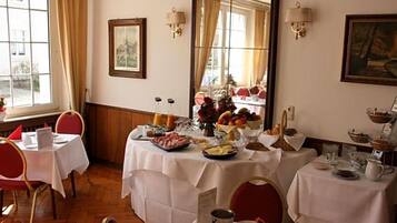 A dining area with tables set for breakfast, featuring a variety of food items and a mirror reflecting the room.