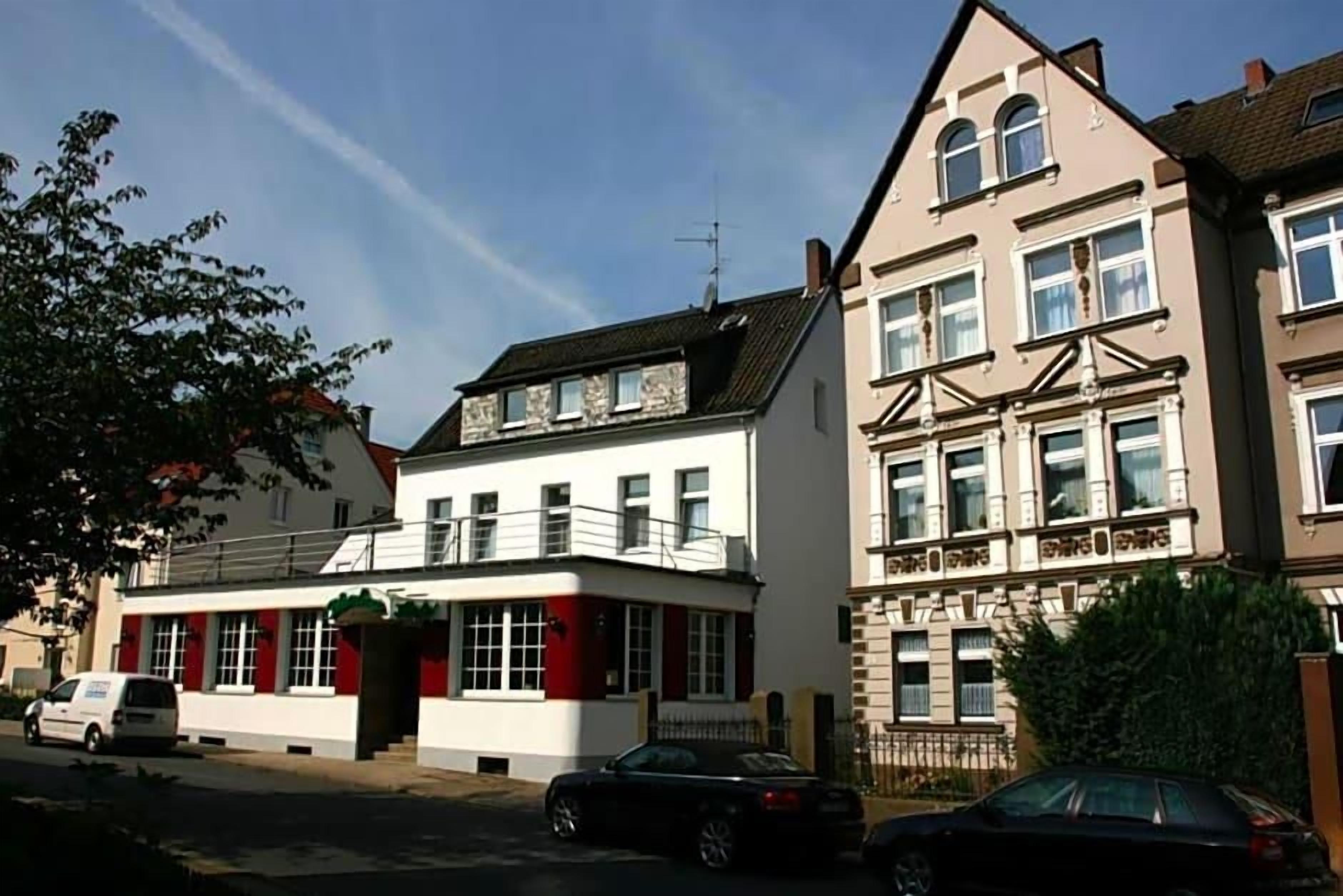 A two-story building with a balcony and a car parked in front.
