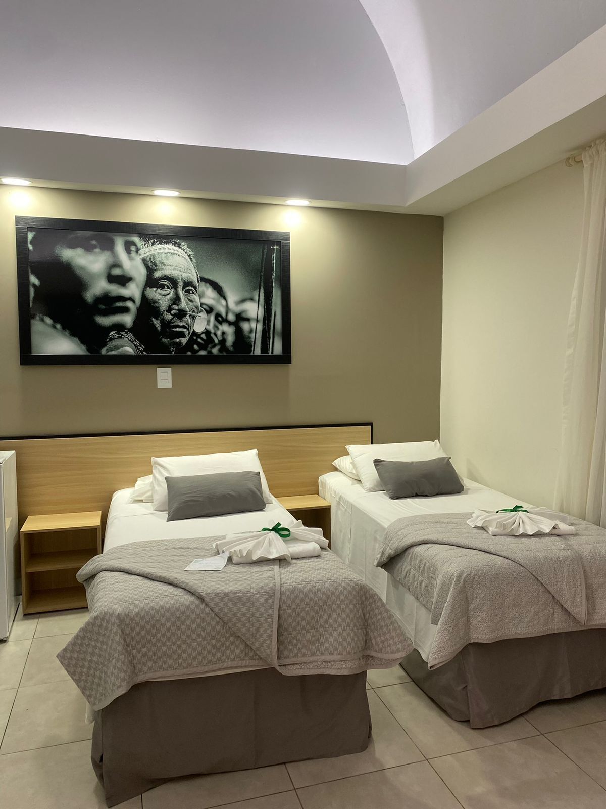 A hotel room with two beds, a large painting on the wall, and a small table.