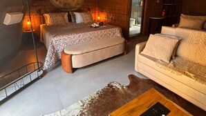 A cozy, rustic room with a bed, sofa, and coffee table, featuring exposed brick walls and a unique ceiling design. - Aj Termas Hotel Iraí (Irai)