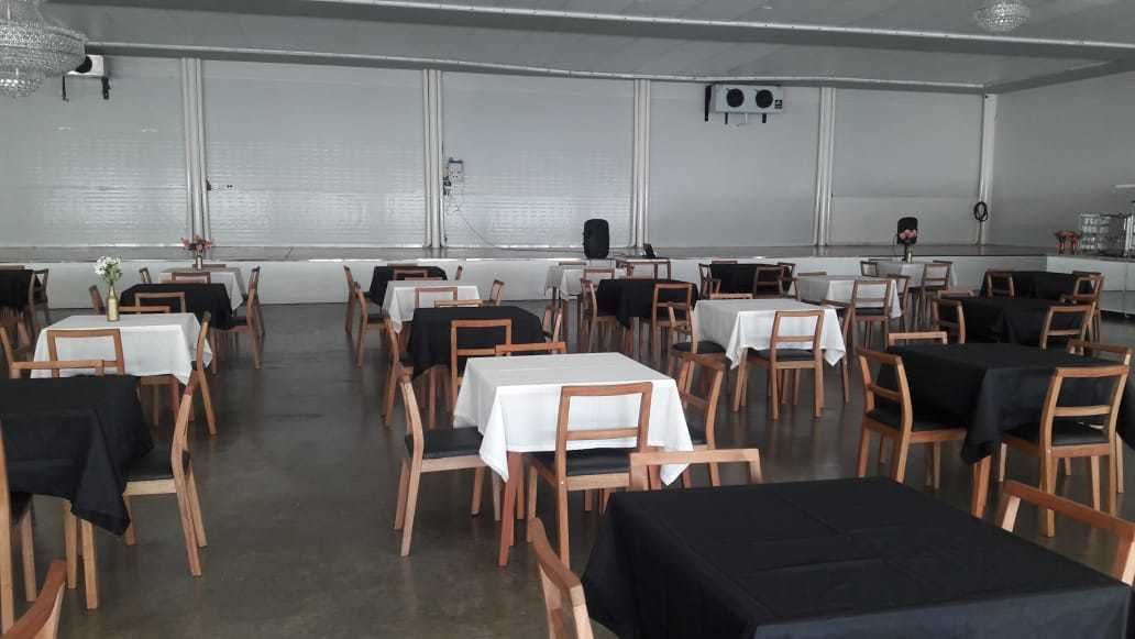 Une grande salle à manger avec de nombreuses tables et chaises, disposées en rangées.