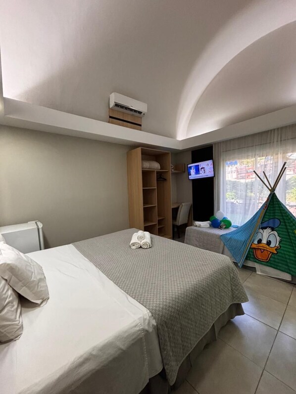 Una habitación de hotel con dos camas, un televisor, un armario y una ventana con vistas.