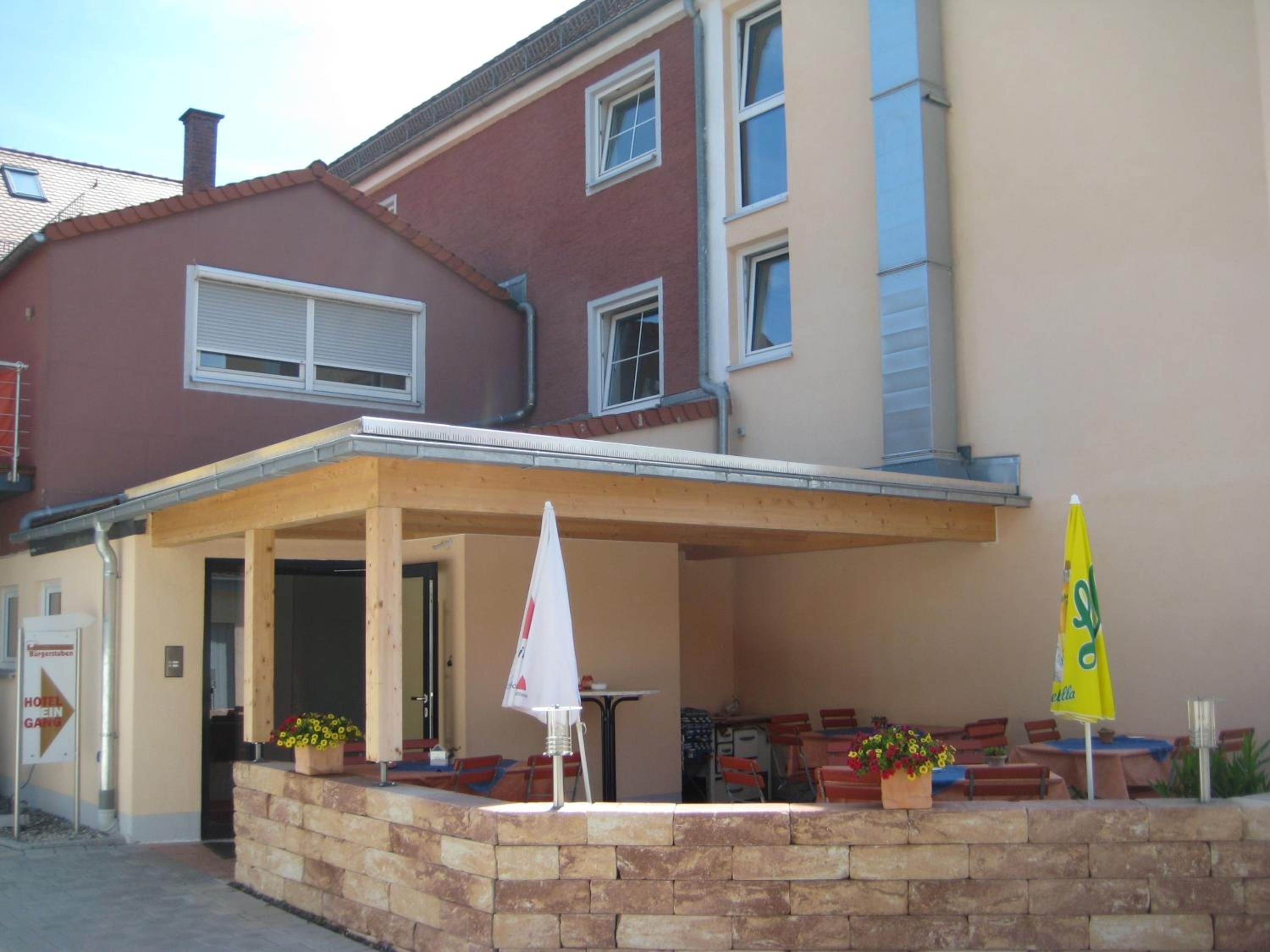 Un hotel con una zona de estar al aire libre techada, un muro de piedra y una bandera.