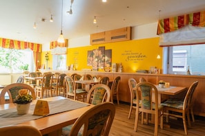 A restaurant interior with wooden furniture, yellow walls, and a menu stand.