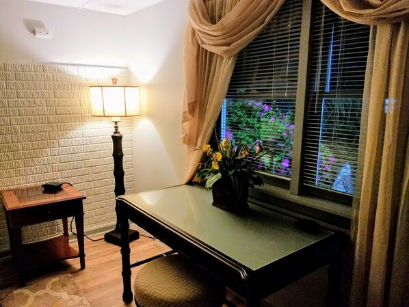 A room with a wooden table, a lamp, a potted plant, and a window with curtains. - Stockbridge Lakes Bed & Breakfast (Stockbridge)
