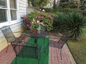A patio with a round metal table and four chairs, surrounded by a garden with various plants and flowers. - Stockbridge Lakes Bed & Breakfast (Stockbridge)