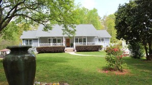 A two-story house with a front porch, a well-maintained lawn, and a flower bed. - Stockbridge Lakes Bed & Breakfast (Stockbridge)