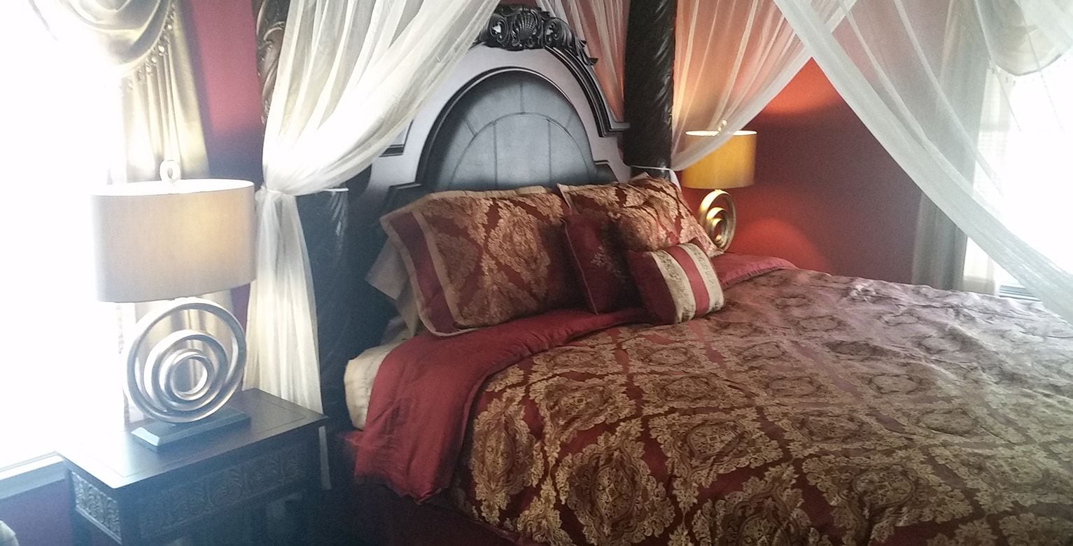 A bedroom with a bed, a nightstand, a lamp, and a window with curtains.