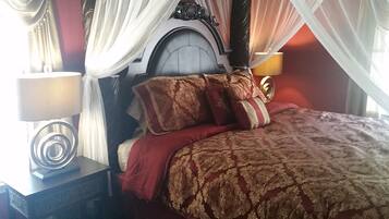 A bedroom with a bed, a nightstand, a lamp, and a window with curtains.