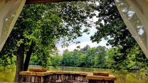 A stone bench overlooking a calm lake surrounded by lush greenery. - Stockbridge Lakes Bed & Breakfast (Stockbridge)