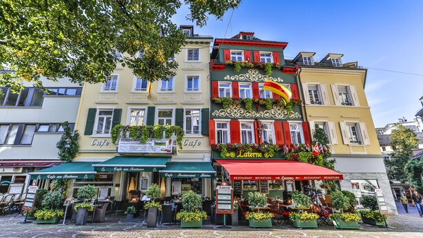 Un café con terraza, un cartel que dice 'Cafe am Rathaus' y un toldo rojo.