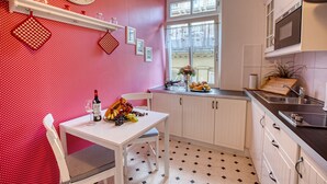 Una cocina con una mesa blanca, un reloj y un ventanal.