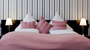 Una habitación de hotel con cama, almohadas y lámparas de noche.