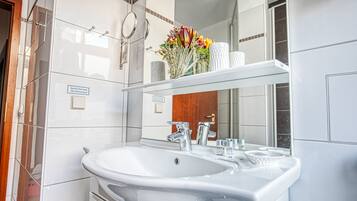 Un baño moderno con un lavamanos grande de color blanco, grifos cromados y un espejo sobre él.