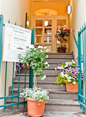 A hotel entrance with a signboard, a staircase with potted plants, and a teal railing. - Suitenhotel Dependance Laterne (Baden-Baden)