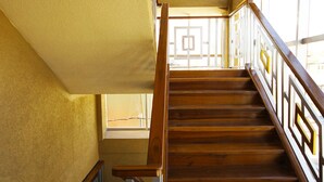 A wooden staircase with a geometric railing design, leading to an upper floor. - Luxury Hotel & Apts (Georgetown)