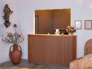 Una recepción con detalles de madera, una estatua en la pared y un florero con flores.