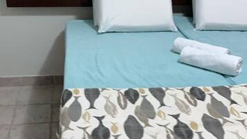 A bed with a patterned bedspread, two white pillows, and a neatly folded towel.