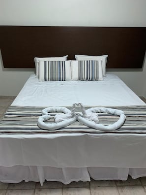 A hotel room with a large bed, striped bedding, and a headboard. - A Cabana (Maceió)