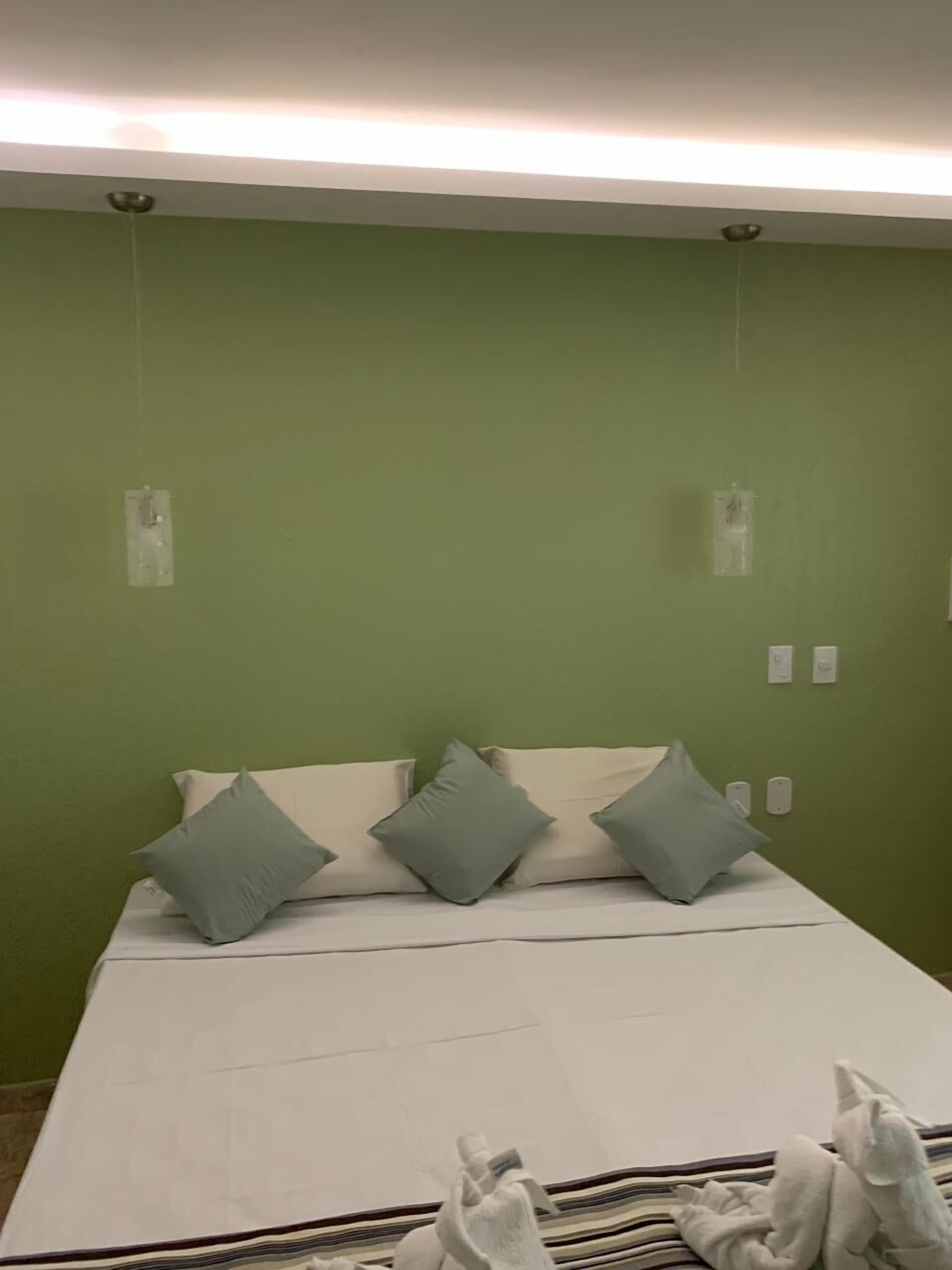 Ett hotellrum med en säng, gröna väggar och en taklampa.