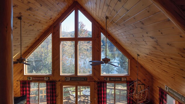 Een chalet met een hoog houten plafond, grote ramen en uitzicht op de natuur.