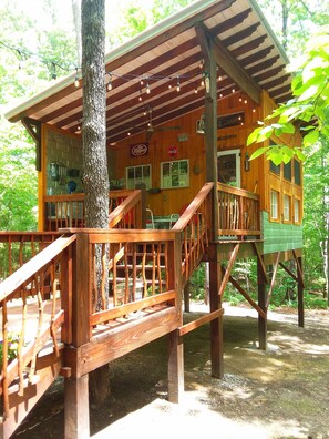 A wooden cabin with a deck, a Coca-Cola sign, and a Dr. Pepper sign. - Glamping at Deer Camp  (Dunlap)