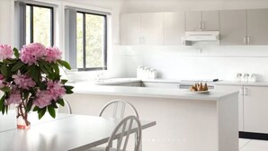 Une cuisine moderne avec des meubles blancs, un grand îlot central et un vase rempli de fleurs roses.