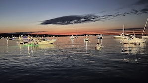 A marina with boats docked at night, calm water, and a sunset sky.