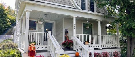 A two-story house with a porch, a staircase, and potted plants.