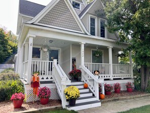 A two-story house with a porch, a staircase, and potted plants.