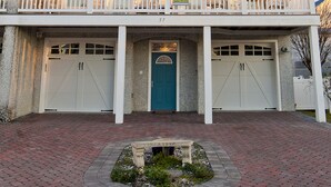 A two-story house with a balcony, a garage, and a front door. - Ocean View 6 Bedroom 4 Bath Home Cooled/Heated Pool No Typical Hidden Fees!! (Tybee Island)