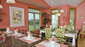A dining area with a table set for four, a large window, and a framed picture on the wall. - Ocean View 6 Bedroom 4 Bath Home Cooled/Heated Pool No Typical Hidden Fees!! (Tybee Island)